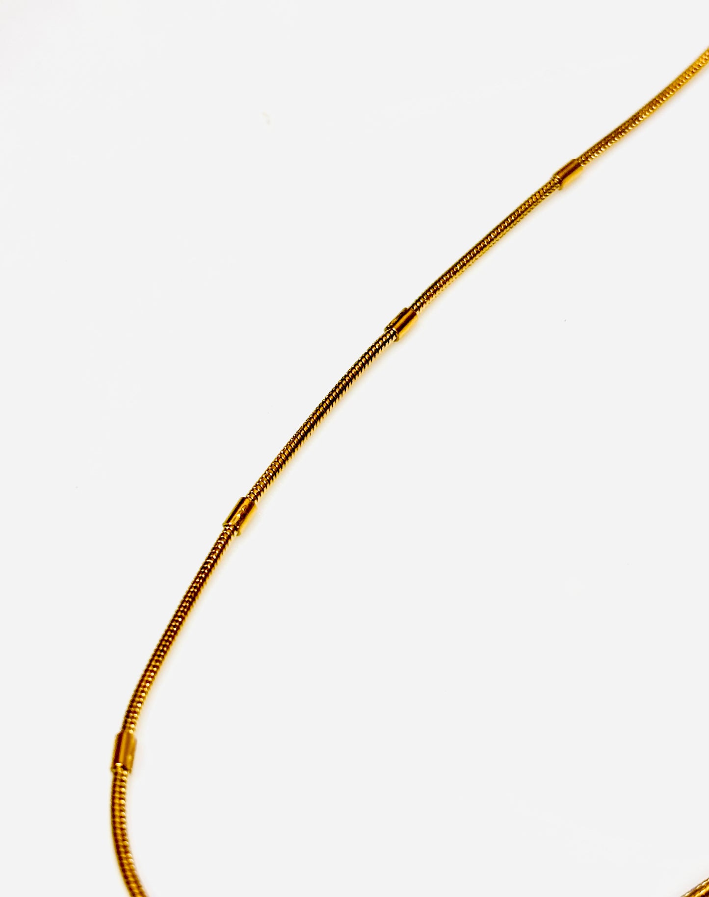 Gold snake chain necklace on a white background