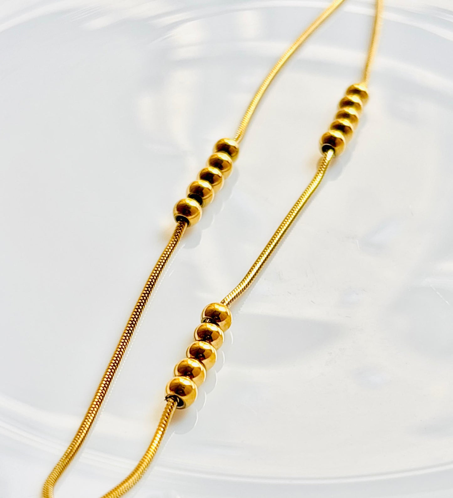 Gold beaded necklace on a white background