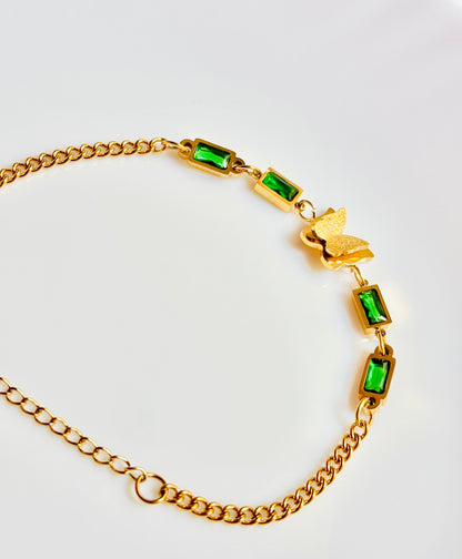 Gold bracelet with green gemstones on a white background