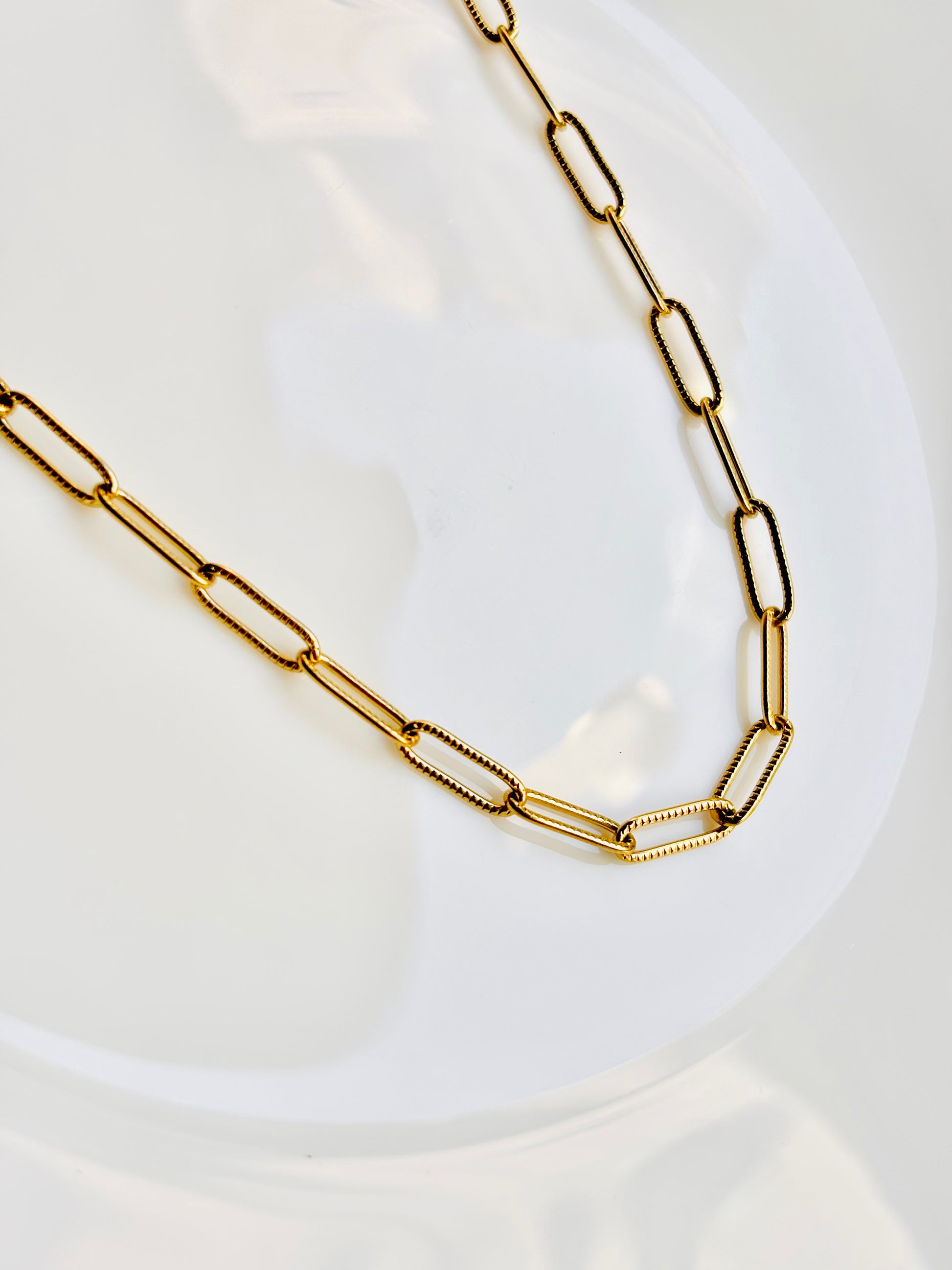 Gold chain necklace on a white plate
