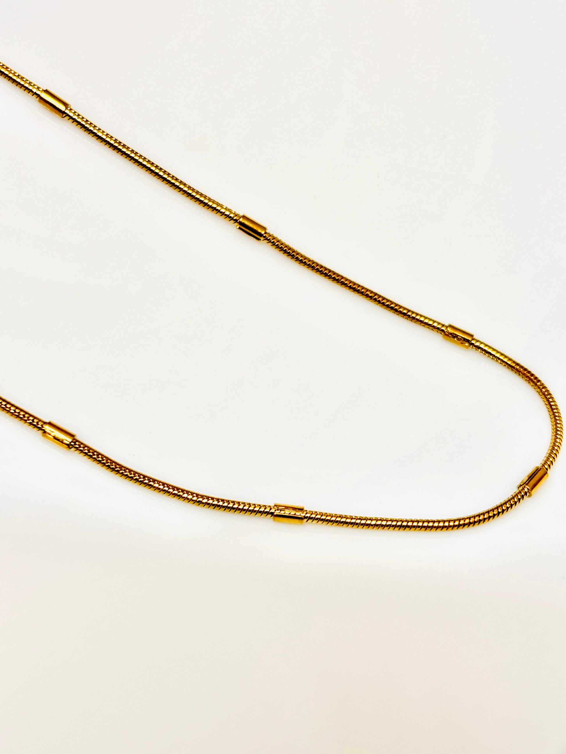 Gold chain necklace on a light beige background