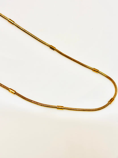 Gold chain necklace on a light beige background