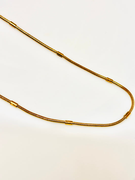 Gold chain necklace on a light beige background