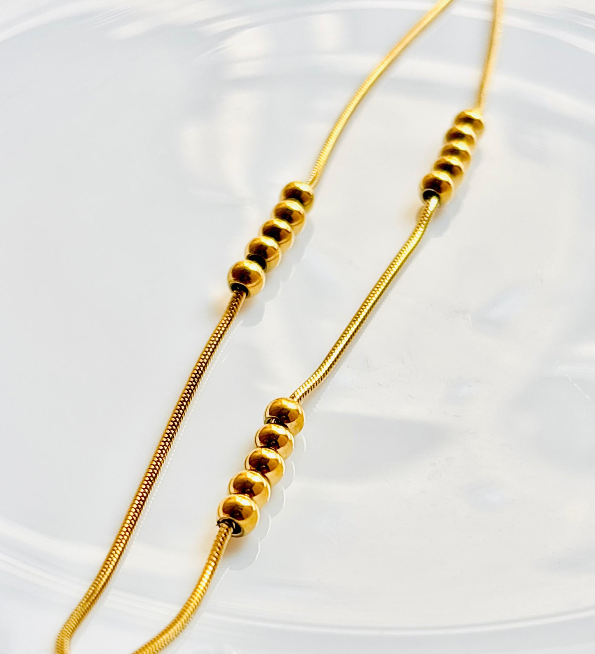 Gold beaded necklace on a white background